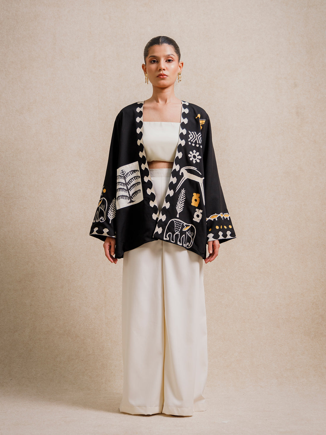 Front view of the Adara Black short kimono worn by a model, featuring hand-printed motifs on a beige background