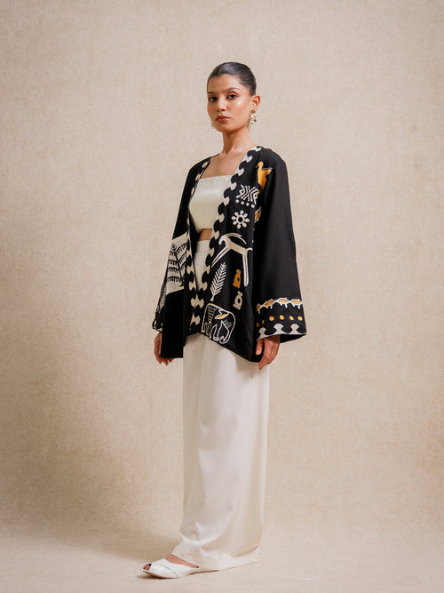 Side view of the Adara Black short kimono worn by a model, featuring hand-printed motifs on a beige background