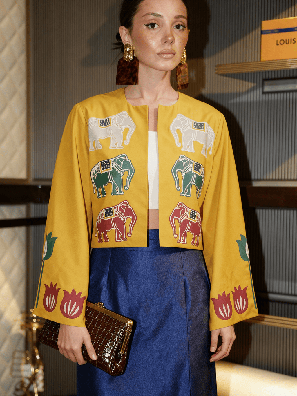 Model wearing the Alam Guman Ochre short jacket with hand-printed elephant motifs in an indoor setting