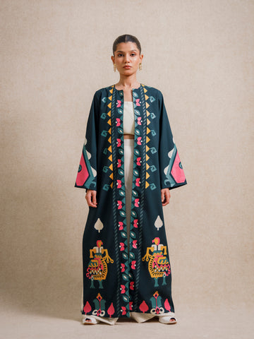 Model wearing Jade Fest Green long jacket with hand screen printed motifs on a beige studio background