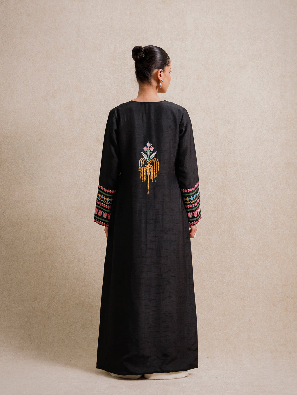 Back view of the Courtyard Dance black long jacket featuring a central hand-printed floral motif and patterned sleeve borders