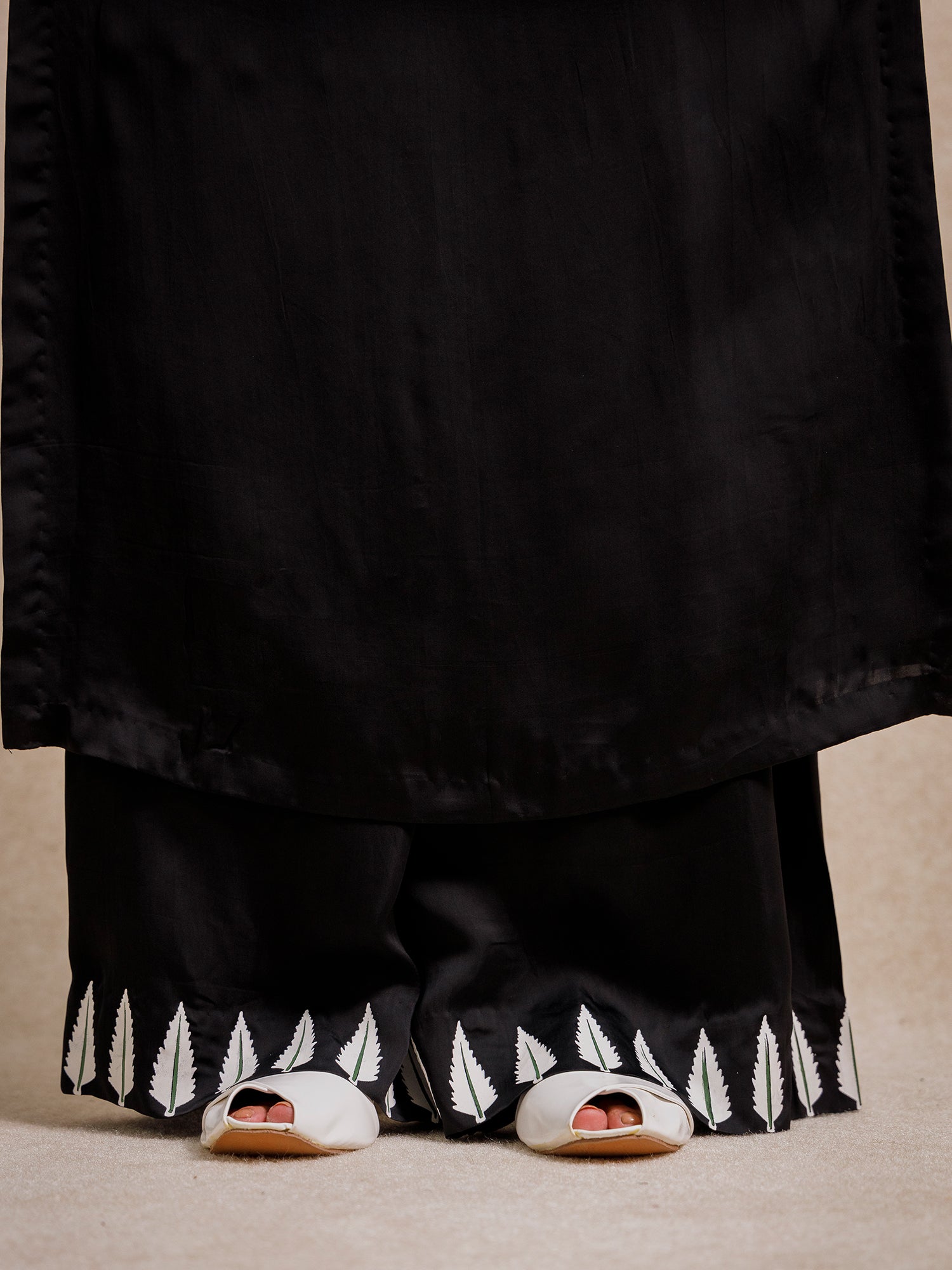 Close-up of Eternal Lovers black trousers featuring hand-printed leaf border detail at the hem