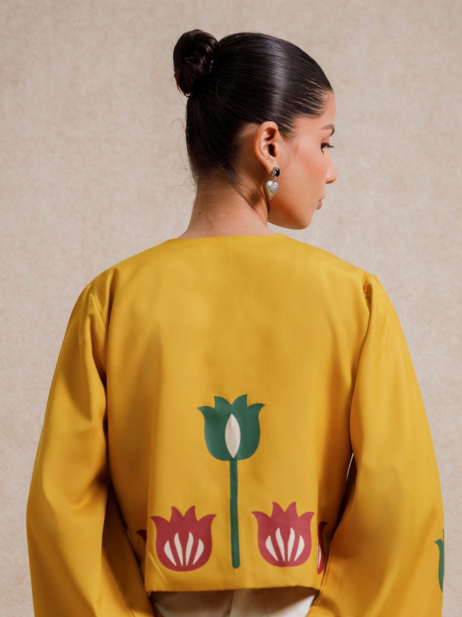 Back view of the Alam Guman Ochre short jacket featuring hand-printed floral motifs on ochre fabric