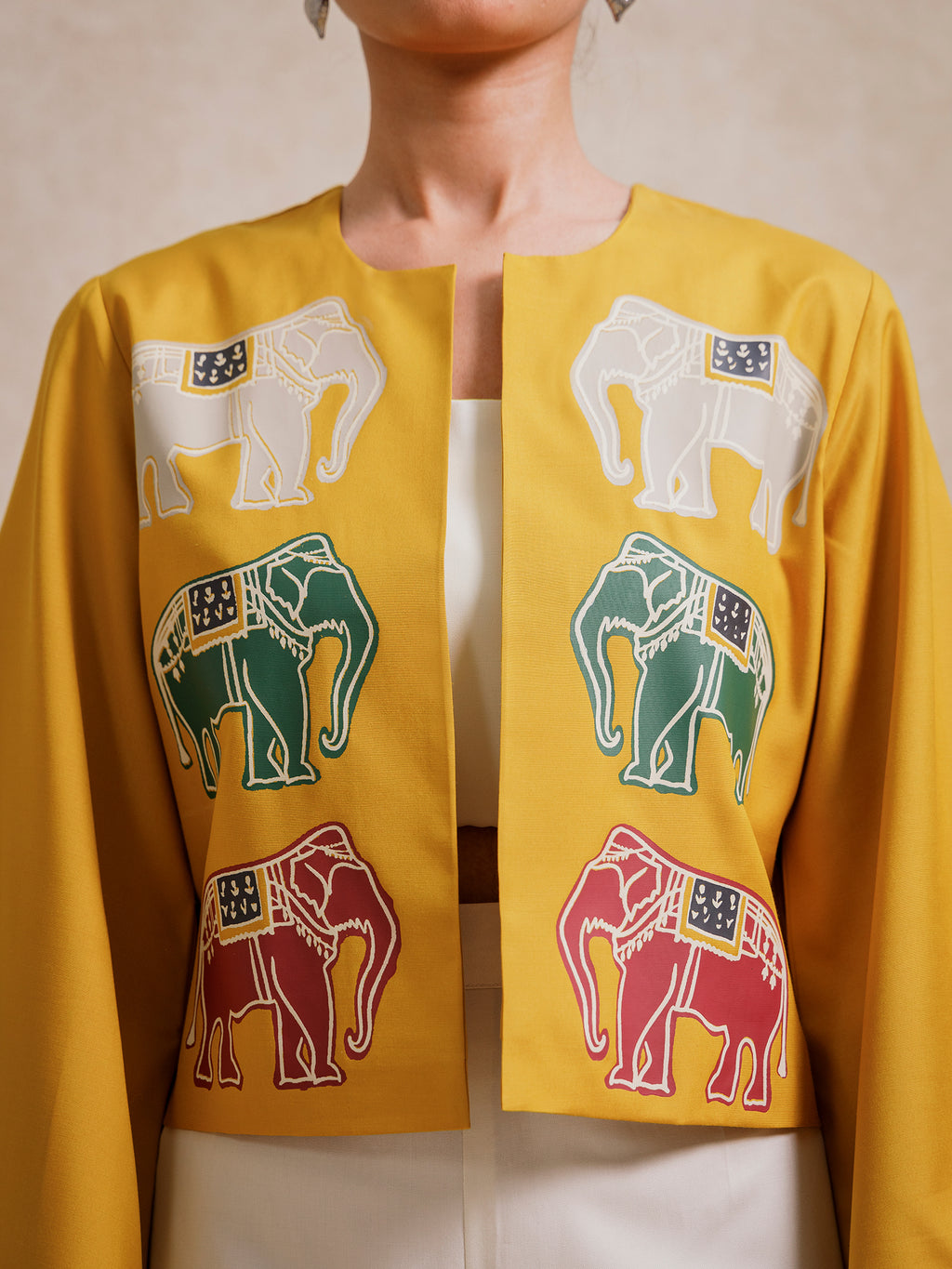 Close-up of the Alam Guman Ochre short jacket showcasing hand-printed elephant motifs on the front panel