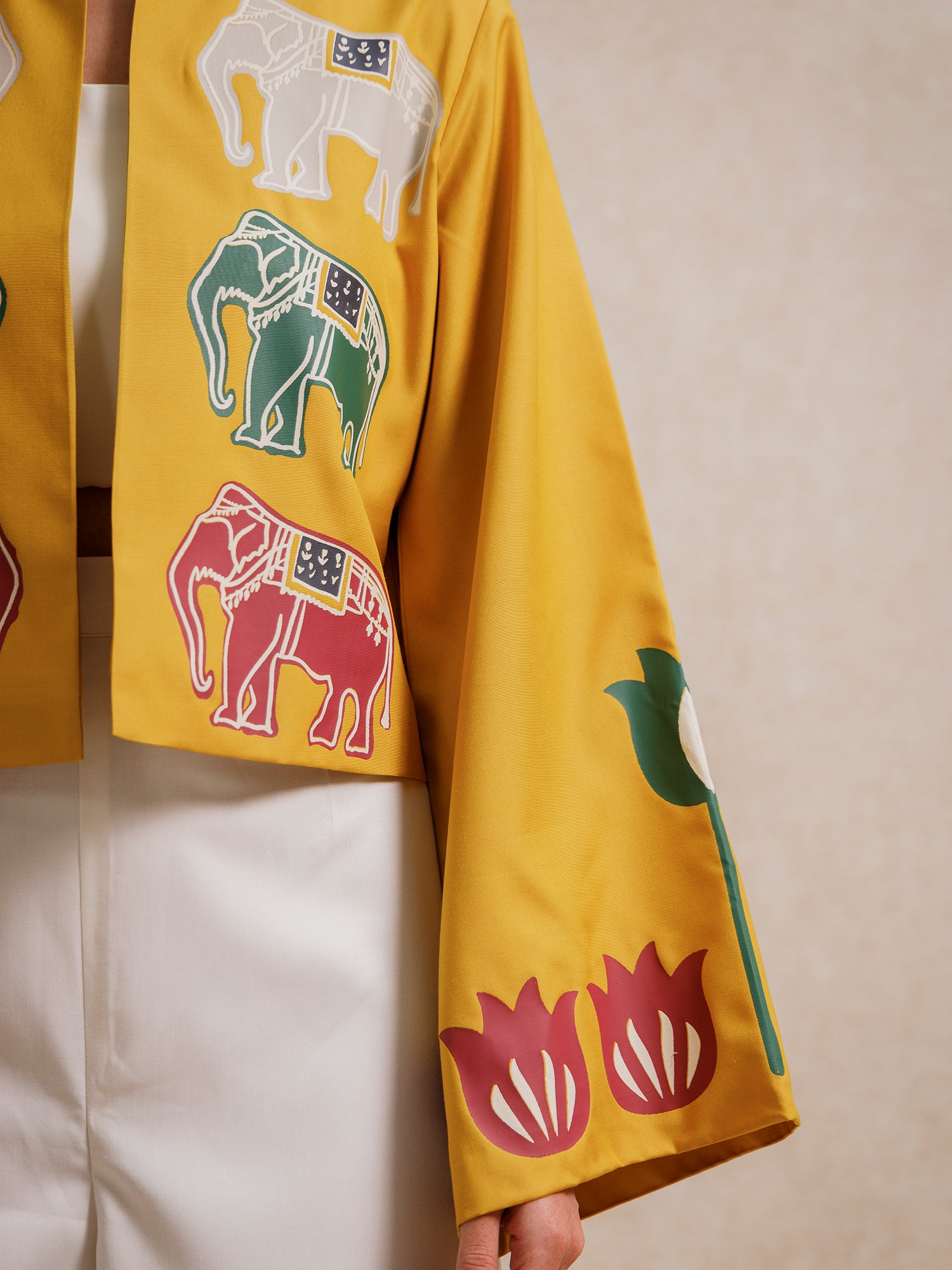 Close-up of the Alam Guman Ochre short jacket sleeve featuring hand-printed elephant and floral motifs on ochre fabric