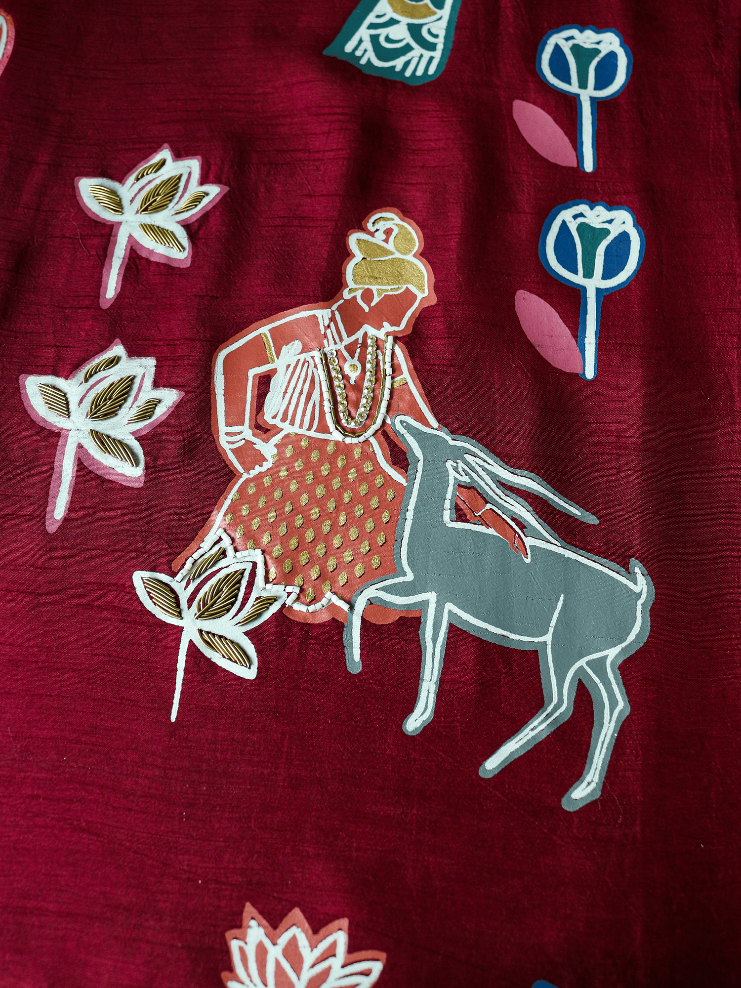 Close-up of hand-embroidered human figure and deer motif on the front of the Forbidden Love Scarlet long jacket by Rangdasti