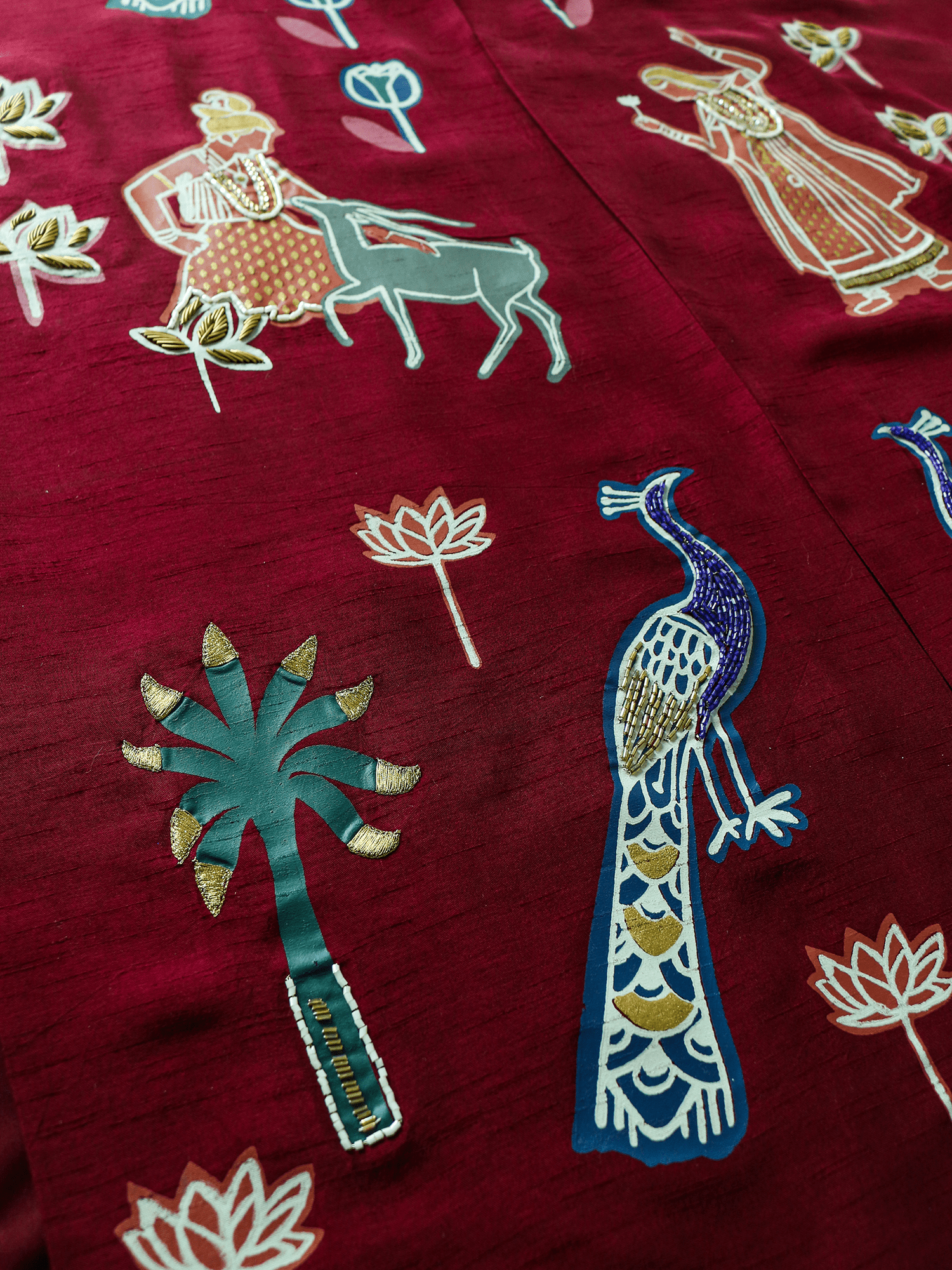 Close-up of hand-embroidered peacock, palm tree, and lotus motifs on the front of the Forbidden Love Scarlet long jacket by Rangdasti