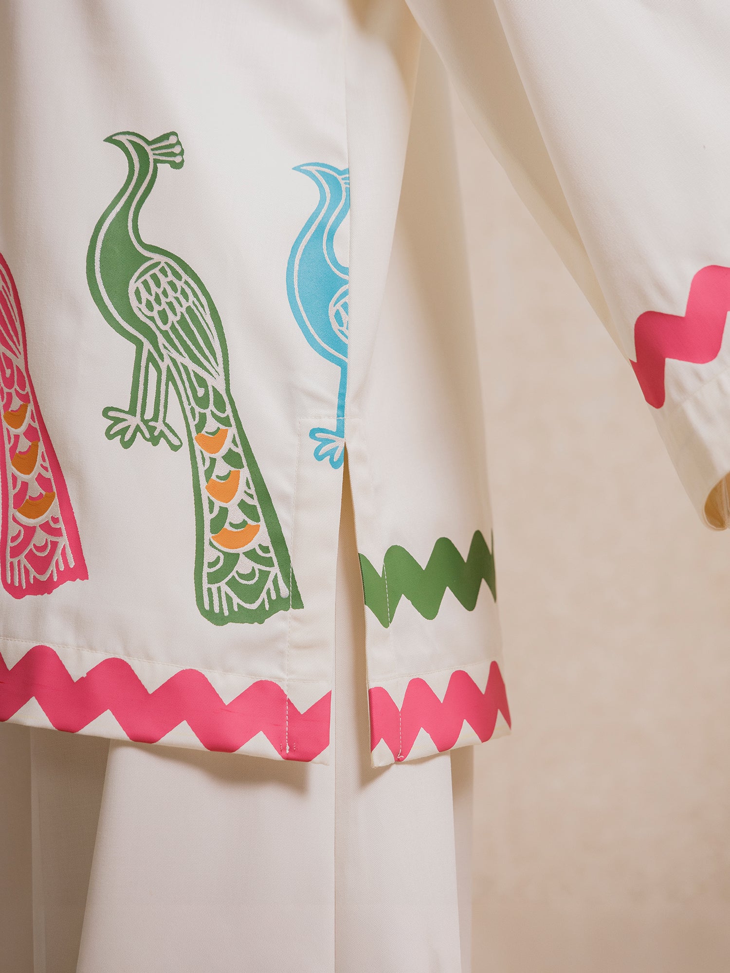 Close-up of Ivory Court two piece set showing bird motifs and scalloped zigzag detailing on ivory fabric